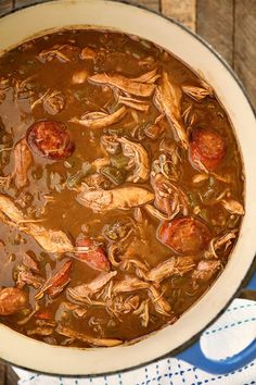 a large pot filled with stew on top of a wooden table next to a blue and white towel