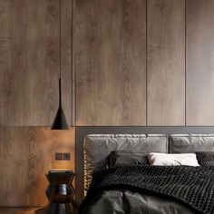 a bedroom with wood paneling and black bedding, along with two nightstands