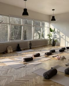 there are many yoga mats on the floor in front of large windows and potted plants