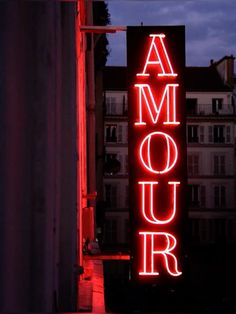 a neon sign that reads amour on the side of a building at night