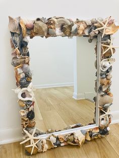 a mirror made out of seashells on a wooden floor