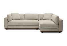 a beige sectional couch with pillows on it