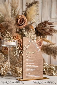 a table topped with a wine glass next to a tall vase filled with flowers and candles