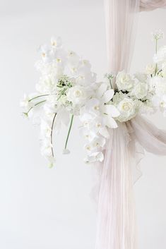 a bouquet of white flowers is tied to a curtain in front of a white wall