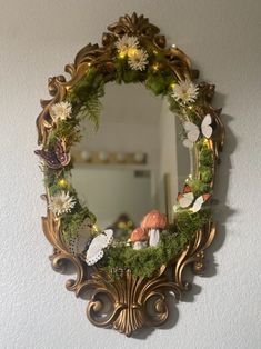 a mirror hanging on the wall with flowers and butterflies in it's centerpiece