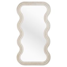 a white mirror with wavy lines on the edges and an oval shaped frame, against a white background