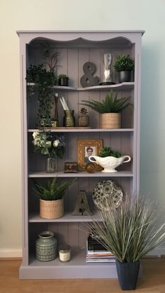 a book shelf with plants and pictures on it