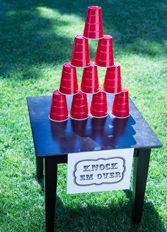 a bunch of red cups sitting on top of a table with a sign underneath it