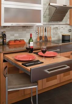 a kitchen counter with two red plates on it and a bottle of wine in the middle