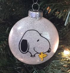 a glass ornament with a cartoon dog on it hanging from a christmas tree