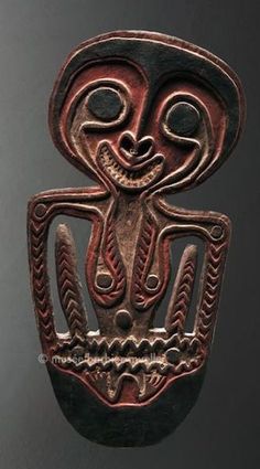 an intricately carved mask hanging from a hook in the shape of a human head