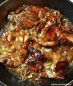 some meat is cooking in a skillet on the stove with sauce and seasoning