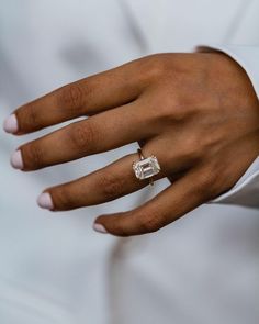 a close up of a person's hand with a diamond ring on their finger