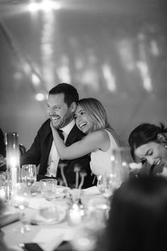 a man and woman hugging each other at a dinner table