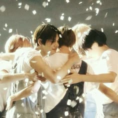 group of young men hugging each other with confetti falling around them