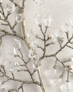 a close up of a tree made out of crystal stones and silver metal wire on a white fabric