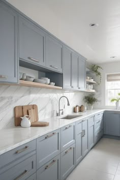 a kitchen with gray cabinets and marble counter tops