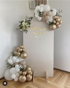 balloons and greenery are arranged on the floor in front of a sign that reads,