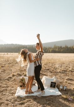 a man and woman standing on top of a blanket in the middle of a field