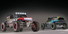 two monster trucks parked side by side in front of each other on a dark background