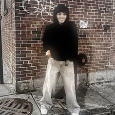 a man standing in front of a brick building with graffiti on the wall behind him