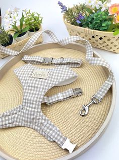 a white and grey gingham dog leash on a round tray with flowers in the background