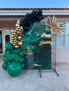 an outdoor birthday party with balloons and decorations in front of a building that says happy birthday