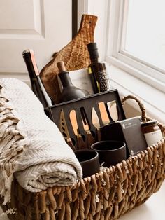 a wicker basket filled with bottles and utensils on a white floor next to a window