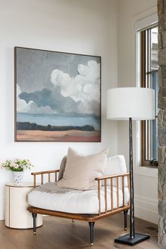 a living room with a couch, lamp and large painting on the wall above it