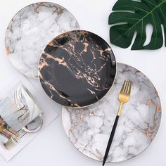 two marble plates with black and gold trim, one has a fork on the plate