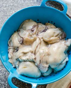 a blue bowl filled with food sitting on top of a table next to a napkin