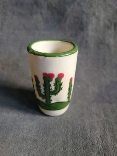 a green and white cup sitting on top of a gray table next to a wall