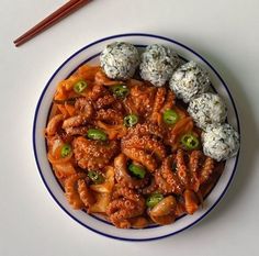 a white plate topped with meat covered in sauce and rice next to chopsticks