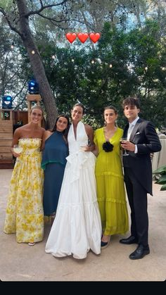 four people posing for a photo in front of a tree with hearts hanging from it