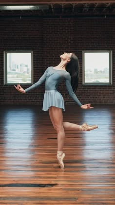 a woman in a blue leotard and ballet shoes is dancing on a wooden floor