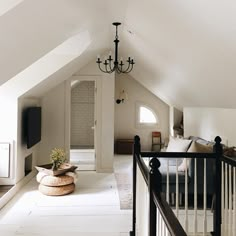 an attic bedroom with chandelier and white walls