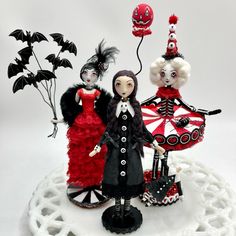 three figurines dressed in black, red and white