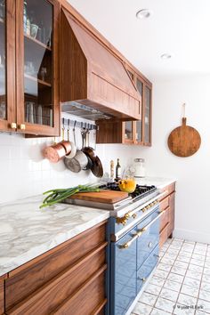 a kitchen with marble counter tops and wooden cabinets, along with hanging utensils