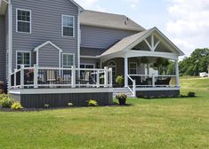 a large gray house sitting on top of a lush green field