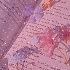 an open book with flowers on it and stars in the sky above them, sitting on a table