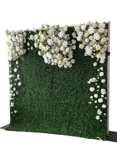 an artificial grass wall with white flowers on it