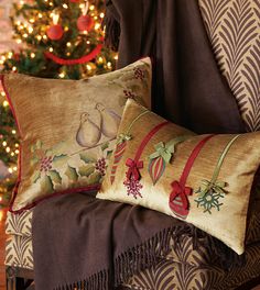 two decorative pillows on a chair in front of a christmas tree