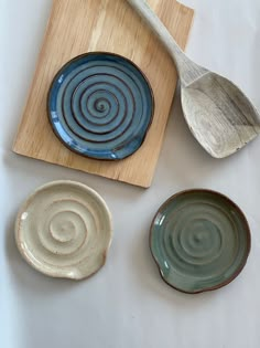 three bowls and two spoons on a cutting board next to each other, one with spiral designs