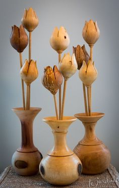 four vases with flowers in them on a table top, one is brown and the other is white