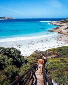 a woman walking up stairs to the beach