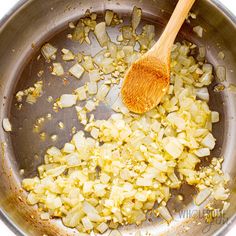 the food is being cooked in the pan with a wooden spoon and some other ingredients