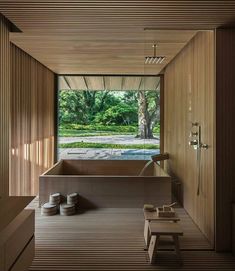 a bathroom with wooden walls and flooring next to a large window that looks out onto the garden