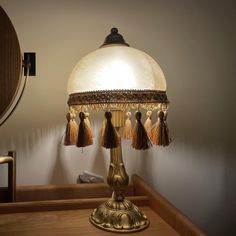 a lamp that is on top of a wooden table with a mirror in the background