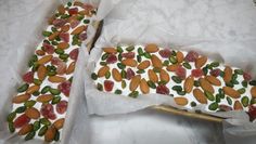 two pieces of cake with nuts and almonds on them sitting in paper wrappers