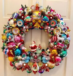 a christmas wreath is hanging on the front door with ornaments all over it and santa's sleigh ornament